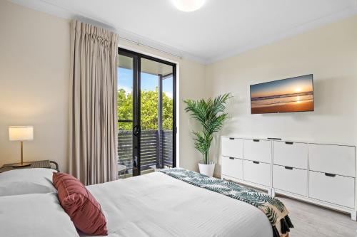 a white bedroom with a bed and a window at Comfy Studio Apartment in Marcoola Beach in Marcoola