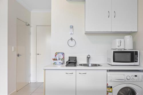 a white kitchen with a sink and a microwave at Comfy Studio Apartment in Marcoola Beach in Marcoola
