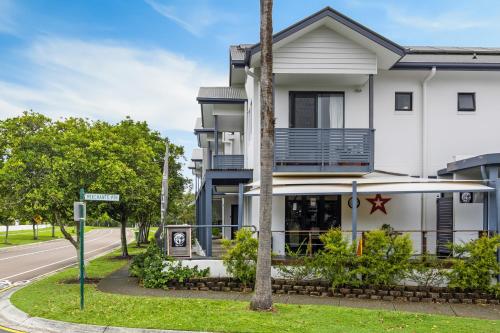 a white building with a balcony on a street at Comfy Studio Apartment in Marcoola Beach in Marcoola