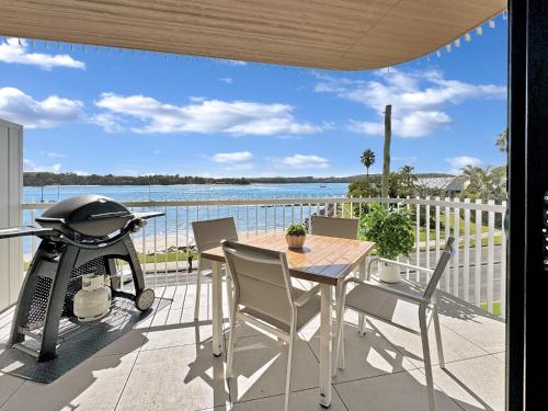 a patio with a table and chairs and a grill at Modern 1-Bedroom Apt with Sweeping Water Views in Batemans Bay
