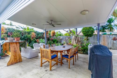 a patio with a table and chairs under a white umbrella at The Little Blue Shack - Quaint Granny Flat in Bli Bli