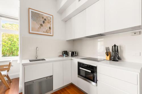 a white kitchen with white cabinets and a sink at Inner-West Studio in a Perfect Location in Sydney