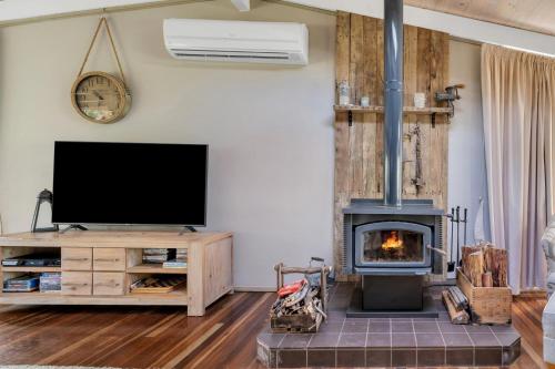 a living room with a television and a fireplace at Secluded 3-Bed Retreat Moments to the Beach in Surf Beach