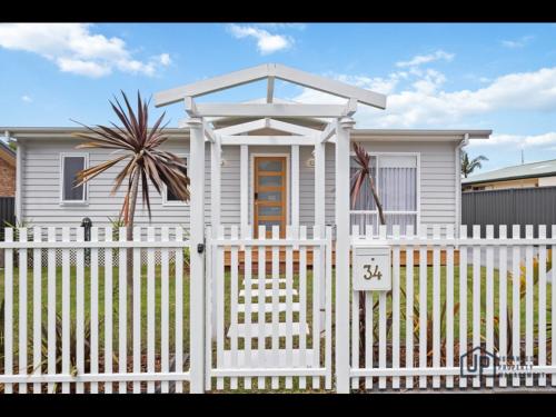 a white fence in front of a white house at Elegant Beachside Retreat with Luxurious Amenities in Tomakin