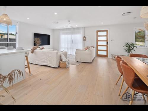 a living room with white furniture and a table at Elegant Beachside Retreat with Luxurious Amenities in Tomakin