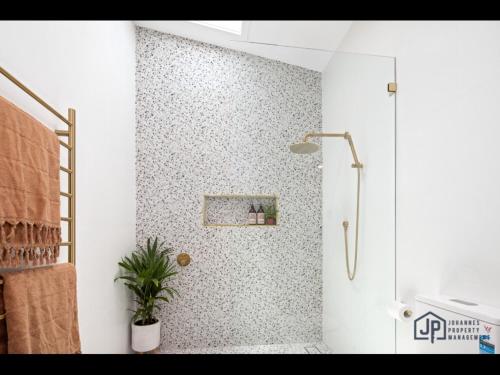 a bathroom with a shower with a plant in it at Elegant Beachside Retreat with Luxurious Amenities in Tomakin