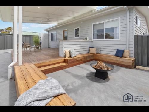 a patio with a fire pit on a house at Elegant Beachside Retreat with Luxurious Amenities in Tomakin