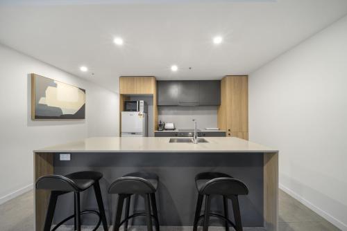 a kitchen with a counter with stools around it at Chic Inner-City 2-Bed Abode with Pool Gym & Sauna in Canberra