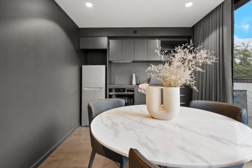 TurnerにあるImmaculate Braddon Studio with Accessible Bathroomの大理石のテーブルと椅子のあるキッチンとダイニングルーム