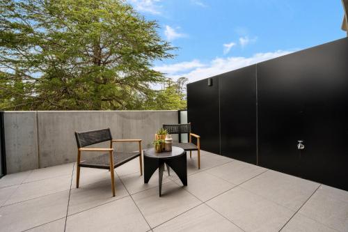 a patio with two chairs and a table on a roof at Braddon Studio with Parking & BBQ in Canberra