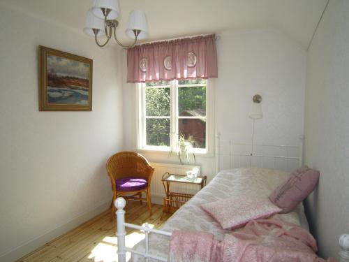 a bedroom with a bed and a window and a chair at Bara Vara Garden in Tösse