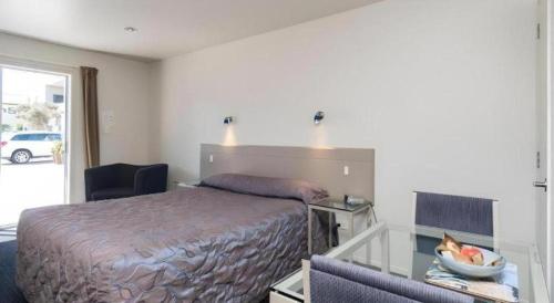 - une chambre avec un lit et un bureau avec une corbeille de fruits dans l'établissement Hawera Central Motor Lodge, à Hawera