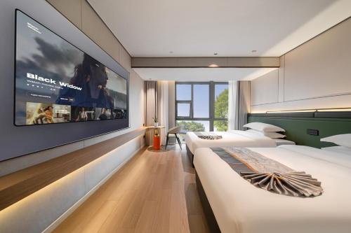 two beds in a hotel room with a large tv at Jiting International Hotel Jiaotong University Light Rail Station in Chongqing