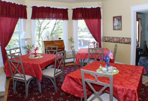 a dining room with two tables with red table cloth at The White Birch Inn in Berwick
