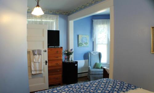 a bedroom with blue walls and a bed and a dresser at The White Birch Inn in Berwick