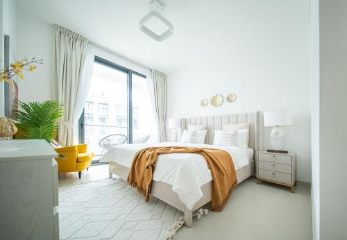 Gorgeous 1 Bed Apartment in Blue Bay Walk في الشارقة: غرفة نوم بيضاء بسرير كبير وكرسي اصفر
