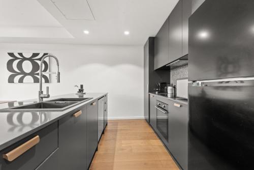 a kitchen with black cabinets and a sink at Stylish 2-Bed in Braddon with Alfresco Dining in Canberra