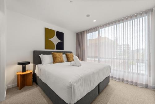 a bedroom with a large bed and a large window at Stylish 2-Bed in Braddon with Alfresco Dining in Canberra