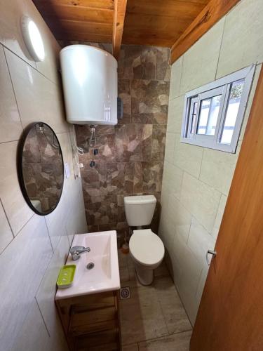 un bagno con un water, un lavandino e uno specchio di Duplex Las Malvinas a Las Toninas