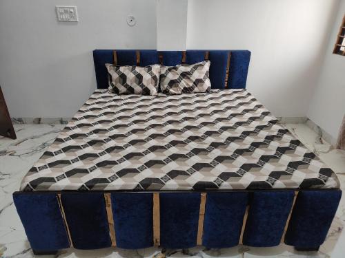 乌贾因Narayan Home Stay的一张蓝色的床,配有黑色和白色的棉被