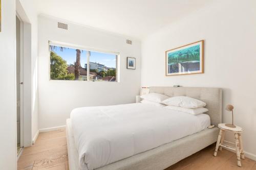 a white bedroom with a bed and a window at Lovely Harbourside 1-Bed Close To Sydney Landmarks in Sydney