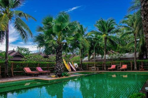 une piscine avec des palmiers et des chaises longues dans l'établissement Baan Baitan Resort, à Ban Tha Fat