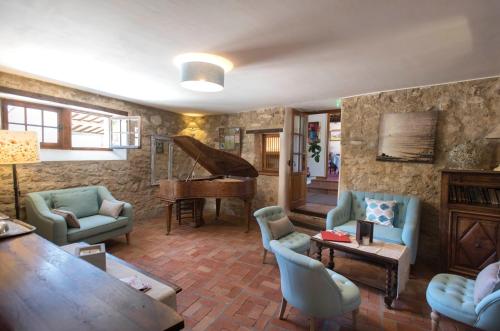 a living room with a piano and blue chairs at Logis Hôtel Les Hospitaliers in Le Poët-Laval