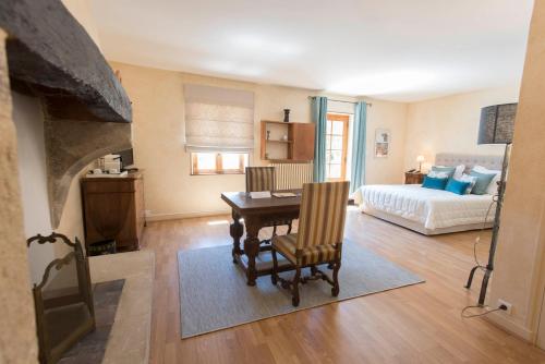 a living room with a table and a bed at Logis Hôtel Les Hospitaliers in Le Poët-Laval