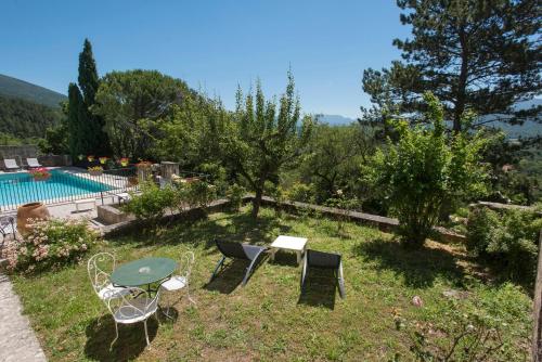 a garden with a table and chairs and a pool at Logis Hôtel Les Hospitaliers in Le Poët-Laval