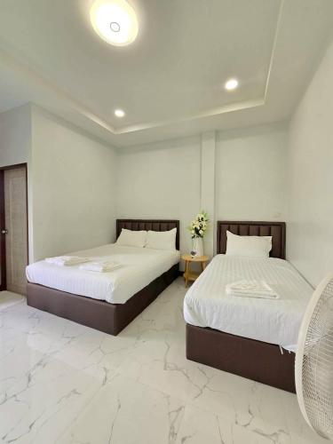 two beds in a room with white walls and marble floors at Remas Homestay Hat Yai in Sathani Khlong Rian