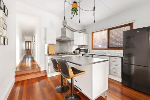 a kitchen with white cabinets and a black refrigerator at Stylish 2-Bed Cottage in Trendy Erskineville in Sydney