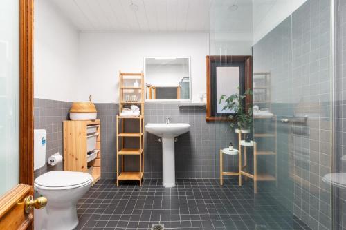 a bathroom with a sink and a toilet and a mirror at Stylish 2-Bed Cottage in Trendy Erskineville in Sydney
