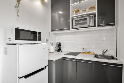 a kitchen with a white refrigerator and a sink at Charming 1-Bed with Fireplace by the Beach in Melbourne