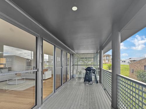a porch with a stroller sitting on a balcony at 2-Bed Beach Haven with Garden & Alfresco Dining in Malua Bay