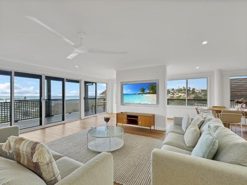 a living room with white furniture and a view of the ocean at 2-Bed Beach Haven with Garden & Alfresco Dining in Malua Bay