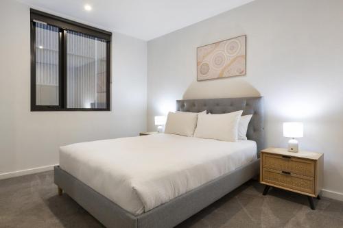 Una habitación blanca con una cama y una ventana en Oceanfront 2-Bed With Balcony & Study Nook, en Geelong