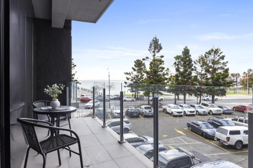 a balcony with a table and a view of a parking lot at Oceanfront 2-Bed With Balcony & Study Nook in Geelong