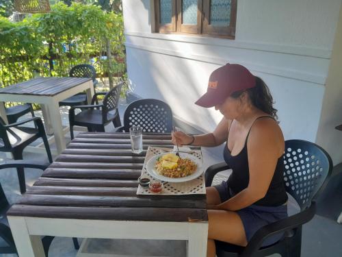 uma mulher sentada à mesa com um prato de comida em Diviya Bungalow and Cantina em Matara