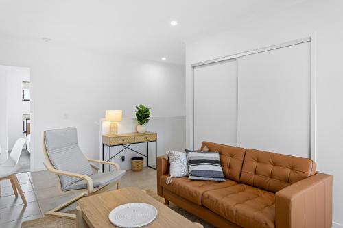 a living room with a brown couch and a chair at Riverside 3-Bed Home with Study Nook and BBQ in Strathpine