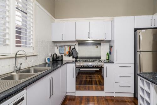 Una cocina con gabinetes blancos y un fregadero. en Incredible 3-Bed Renovated Home with Huge Garden, en Perth