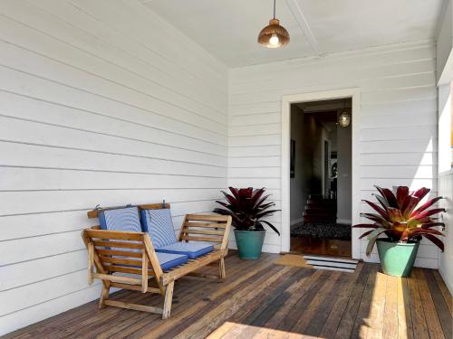 a porch with two chairs and two potted plants at 3-Bed Coastal Haven with Alfresco Dining & BBQ in Marks Point