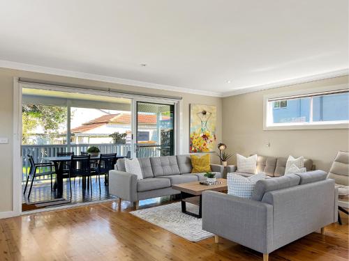 a living room with a couch and a table at 3-Bed Coastal Haven with Alfresco Dining & BBQ in Marks Point