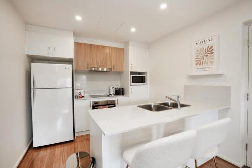 a white kitchen with a sink and a refrigerator at Ground Level 1-Bed: Courtyard & Alfresco Dining in Weston Creek