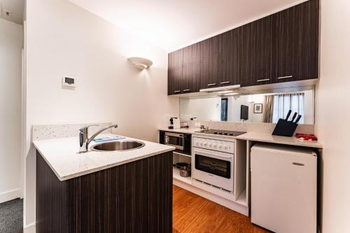 a kitchen with a sink and a stove top oven at Chic 1-Bed in East Melbourne with Gym & Pool in Melbourne