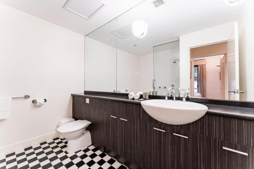 a bathroom with a sink and a toilet and a mirror at Chic 1-Bed in East Melbourne with Gym & Pool in Melbourne