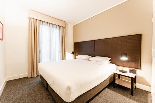 a bedroom with a large white bed and a window at Chic 1-Bed in East Melbourne with Gym & Pool in Melbourne