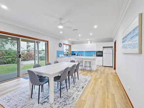 a kitchen and dining room with a white table and chairs at 4-Bed Beach House with Garden & Alfresco Dining in Tomakin