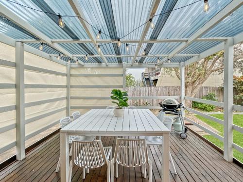 a white table and chairs on a deck with a blue ceiling at 4-Bed Beach House with Garden & Alfresco Dining in Tomakin