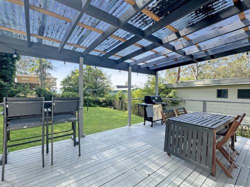 a wooden deck with a pergola and a table and chairs at Pet-Friendly 2-Bed Beach House with Garden & BBQ in Surf Beach