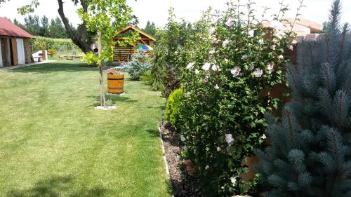 a garden with a bush with flowers and a house at Chalupy Majer Biffar in Dunajský Klátov